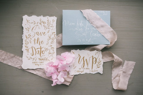 Wedding Invitation suite including a save the date card lying on a table with ribbon