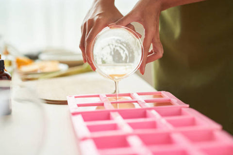 Pouring clear soap base into pink square molds