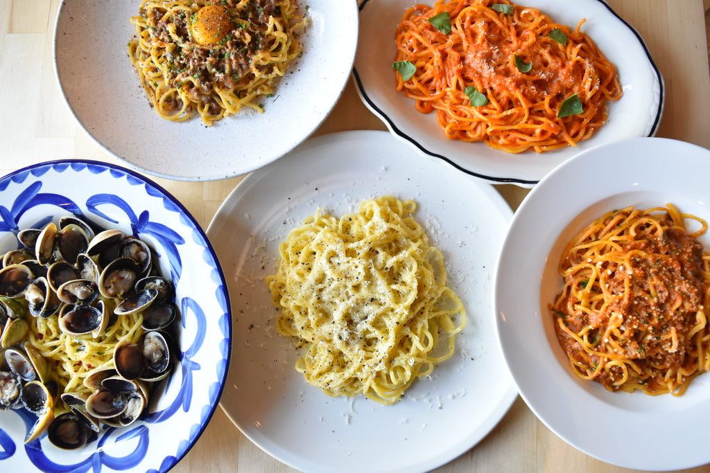 A birds eye view of 5 different pasta dishes arranged on a table