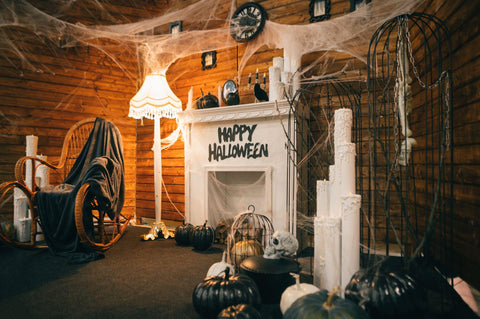 The cozy photo area is decorated for Halloween with a fireplace and an armchair and All Hallows Even elements. 