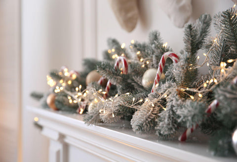 Beautiful decoration of fir tree branches, candy canes, fairy lights and Christmas balls in room