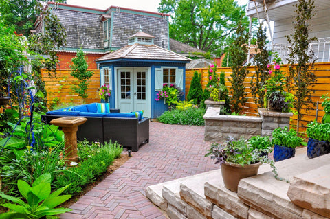 Beautiful small backyard garden features a seat wall, red brick paver herringbone patio, high end shed