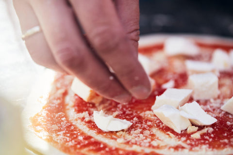 Cheese is placed on the pizza dough with sauce.