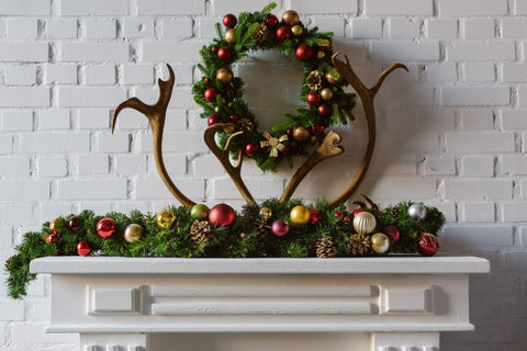 christmas wreath with decorations and deer horns over fireplace mantel