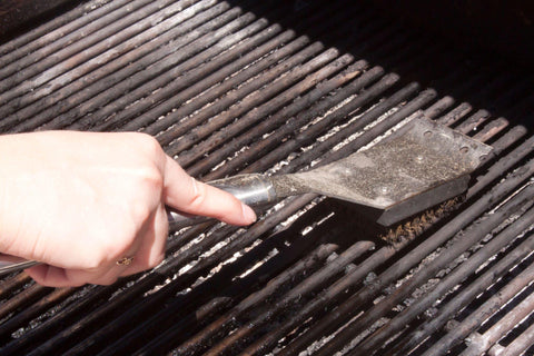 Cook hands with metal brush clean the grill
