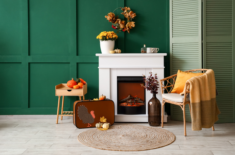 Fall decorations on a mantel with green wall paint.