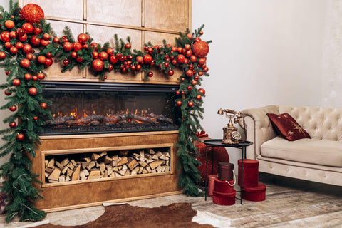 Green Christmas garland above fireplace with red ornaments.