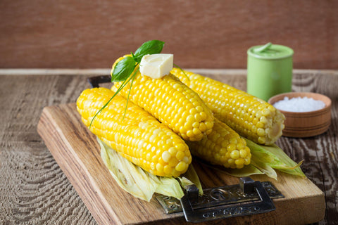 Homemade boiled corn on cob with butter and salt on rustic woode