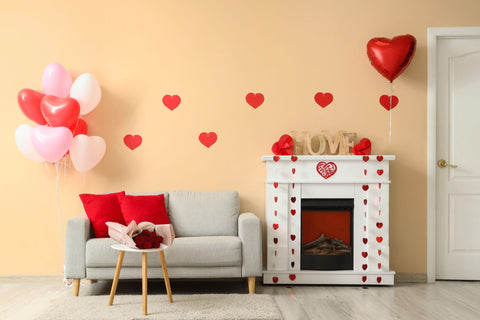 Interior of festive living room with grey sofa, fireplace and decorations for Valentine's Day celebration.