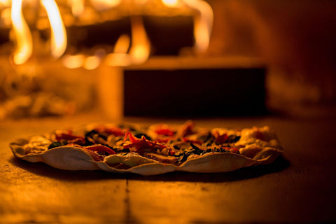 pizza is cooked in a wood-fired oven