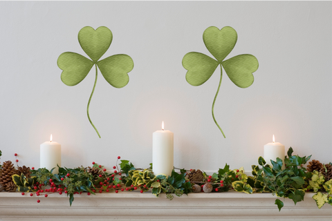 Two green clovers on wall above white mantel with candles.