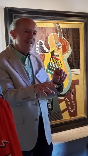 Gary T. Erbe at his opening for the show, imaged in front of his painting, The Green-Eyed Amp