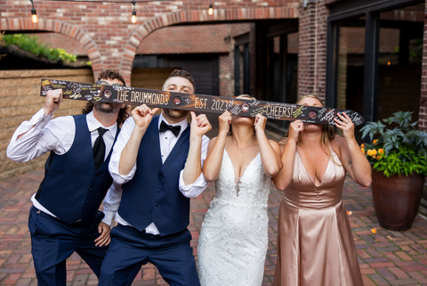Bride and groom taking a shot with bridal party at wedding reception. Bride in wedding dress and groom in tuxedo