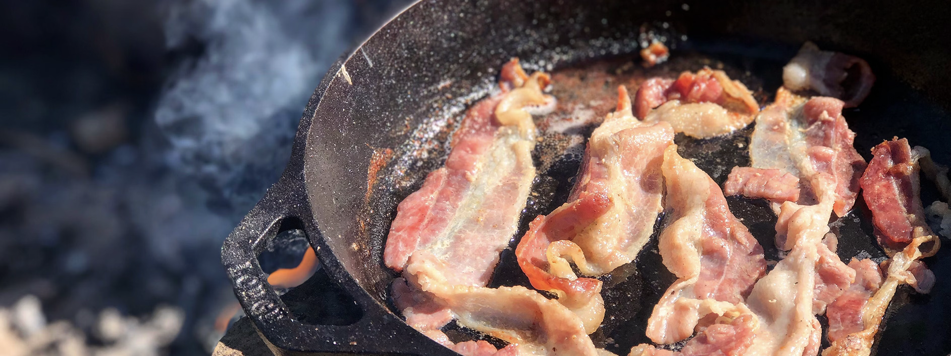 Bacon Sizzling in Cast Iron Skillet