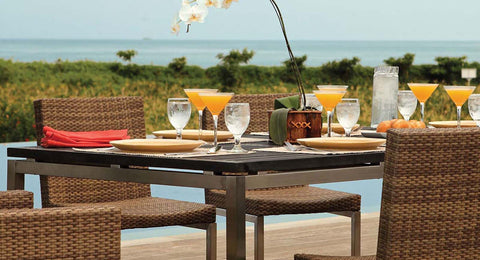 Four chairs around a table in front of a blue pool and open sea.