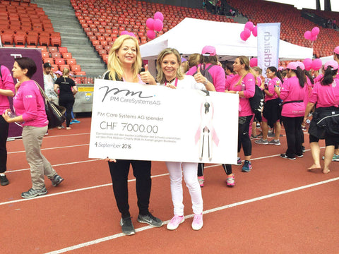 Doris Merz von PM Care Systems übergibt eine Spende an Pink Ribbon Schweiz.