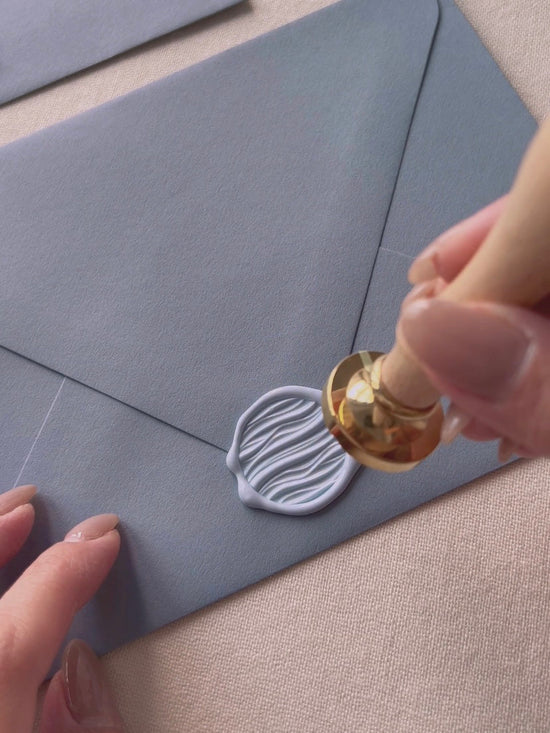 Wax sealing with 3D Waves wax stamp on dark sage envelope