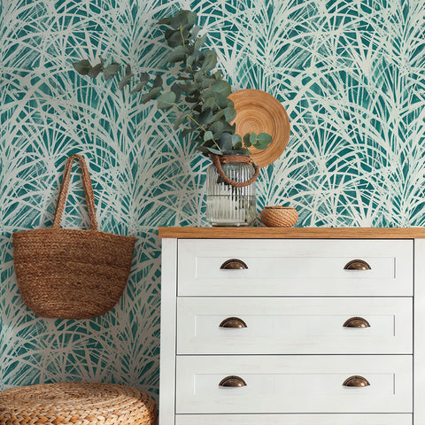 Teal Grassroots wallpaper behind a dresser and seat.