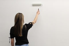 Girl rolling wallpaper paste on the wall for wallpaper application