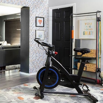 Image by @albieknows. Workout space with a peloton bike, resistance bands and wallpaper on the wall.
