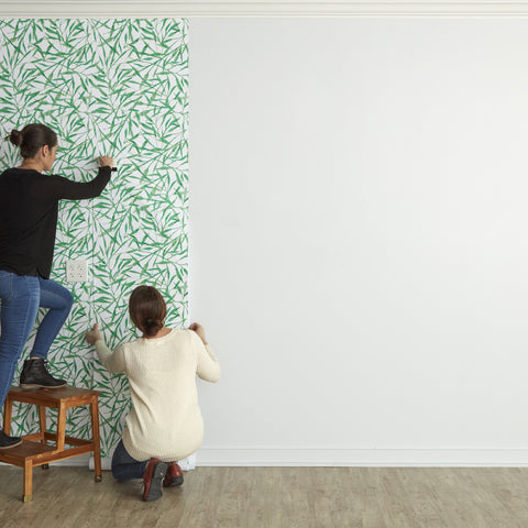 2 friends installing green leaves peel and stick wallpaper