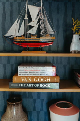 Geo grasscloth wallpaper lines a bookshelf