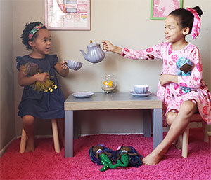 Winter and Willow having a tea party. Winter pouring tea for Willow while holding dolls.