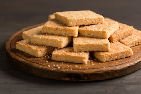 Stack of shortbread cookies on a round wooden chopping board.