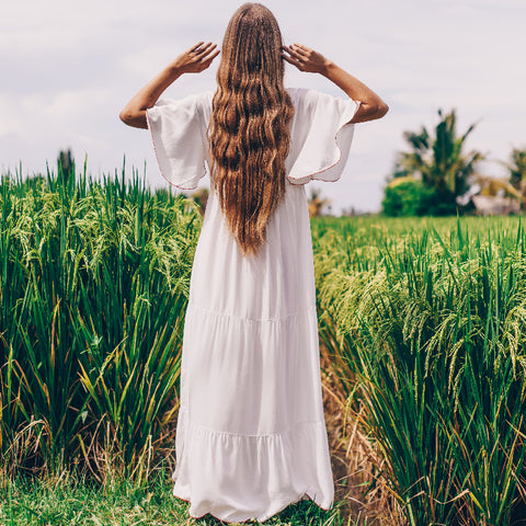 women in a field of green grass with a white long dress bohemain