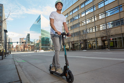 Man riding down the street on a GOTRAX Black Apex Electric Commuter Scooter for Adults