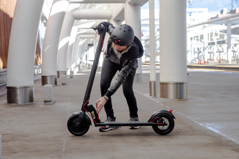Women folding GOTRAX Black GXL V2 Electric Scooter for Adults into the folded position. 
