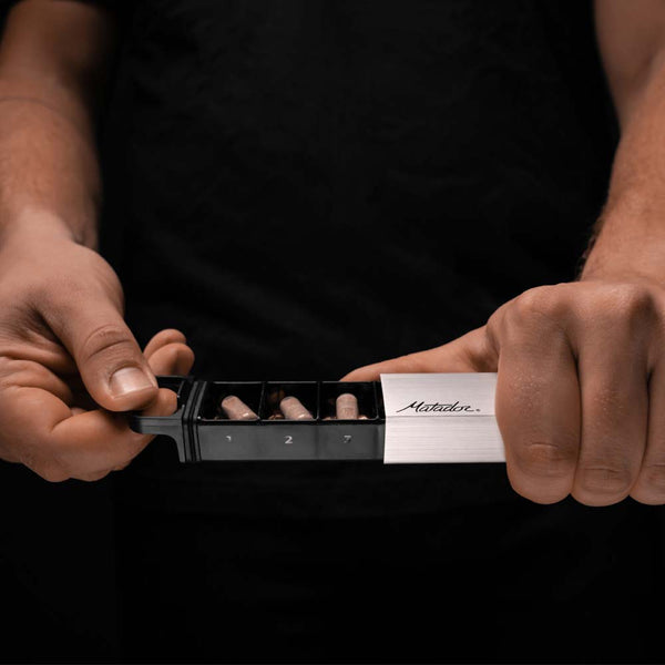 Hands opening pill canister on dark background