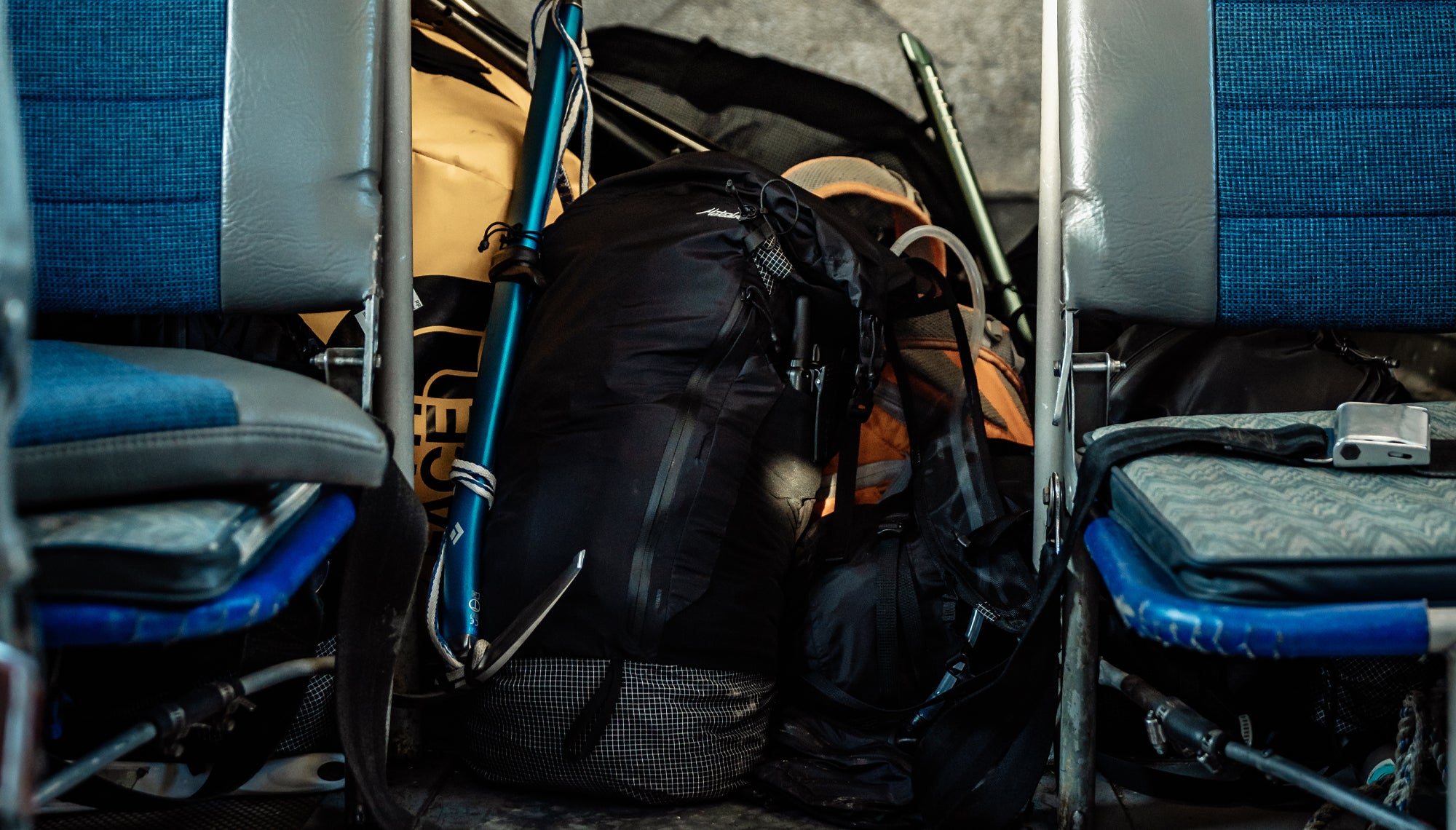 Backpack in a pile of gear between plane seats