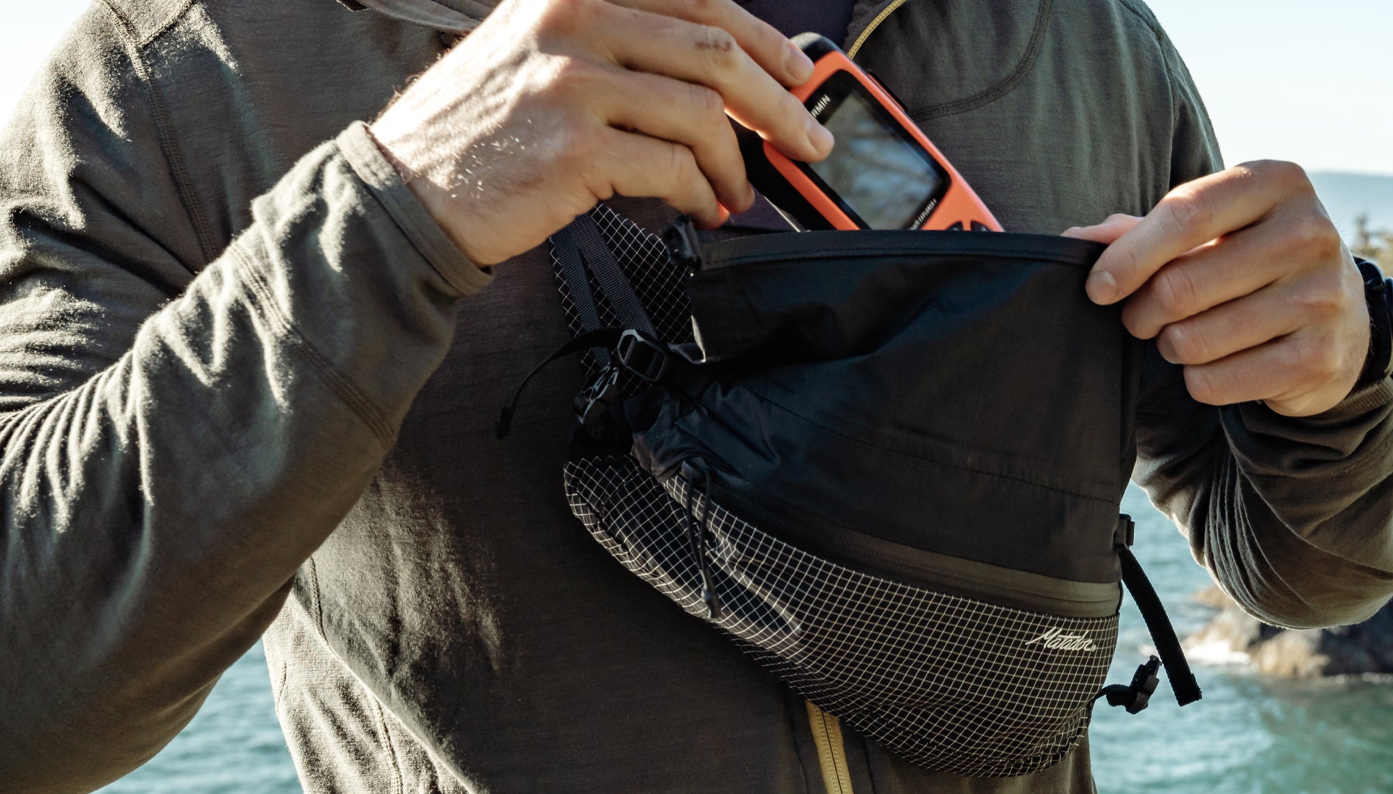 Man placing GPS device into cross body hip pack