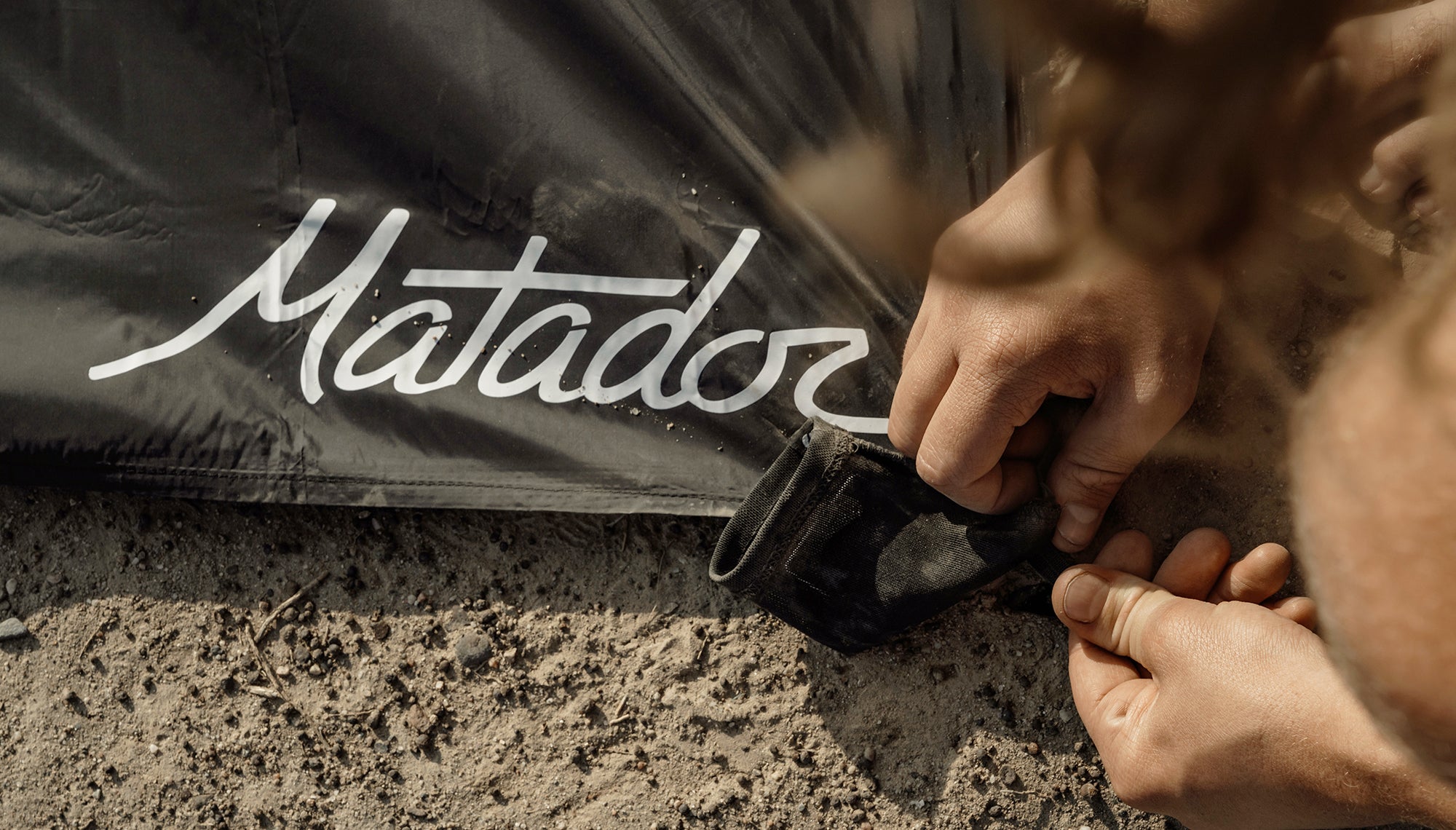 Man staking pocket blanket into sand