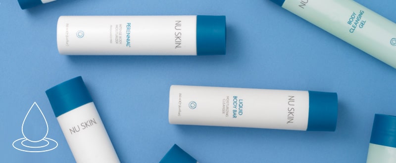 Mehrere NuSkin Basic Produkte liegen durcheinander auf glatter dunkelblauer Oberfläche, darunter auch NuSkin Body Cleansing Gel.