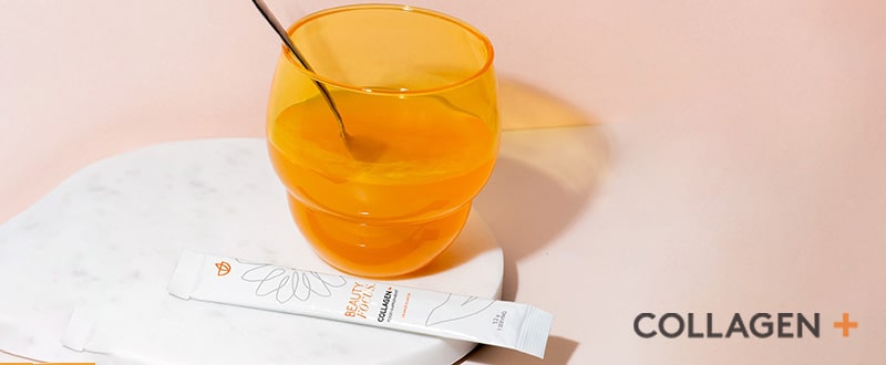 niedriges orangenes Glas mit angerührtem Beauty Focus™ Collagen+ Pulver. Das dazugehörige Päckchen liegt davor.