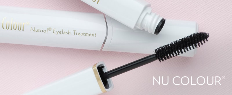 Nu Colour Nutriol Eyelash Treatment liegt geöffnet auf glatter hellrosa Oberfläche.