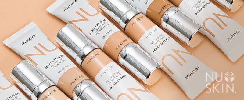 Nu Colour Bioadaptive BB+ Skin Loving Foundation Tuben liegen dicht nebeneinander auf bescher glatter Oberfläche.