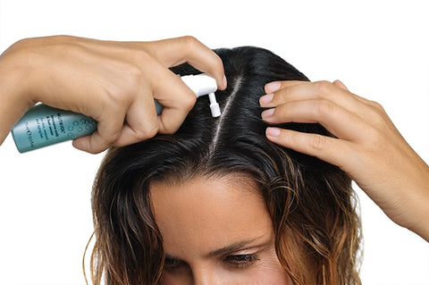 Nauaufnahme, leichte Aufsicht: Frau gibt das ageLOC Nutriol Intensive Scalp & Hair Serum auf ihren Ansatz auf.