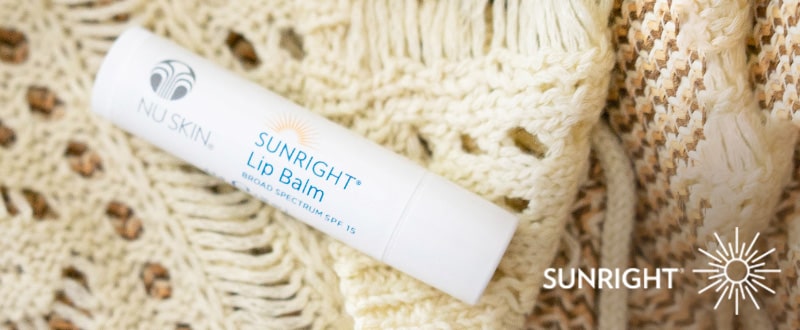 Sunright Lip Balm 15 von NuSkin (Größe 4,2g) liegt geschlossen auf einer weißen Strickdecke.