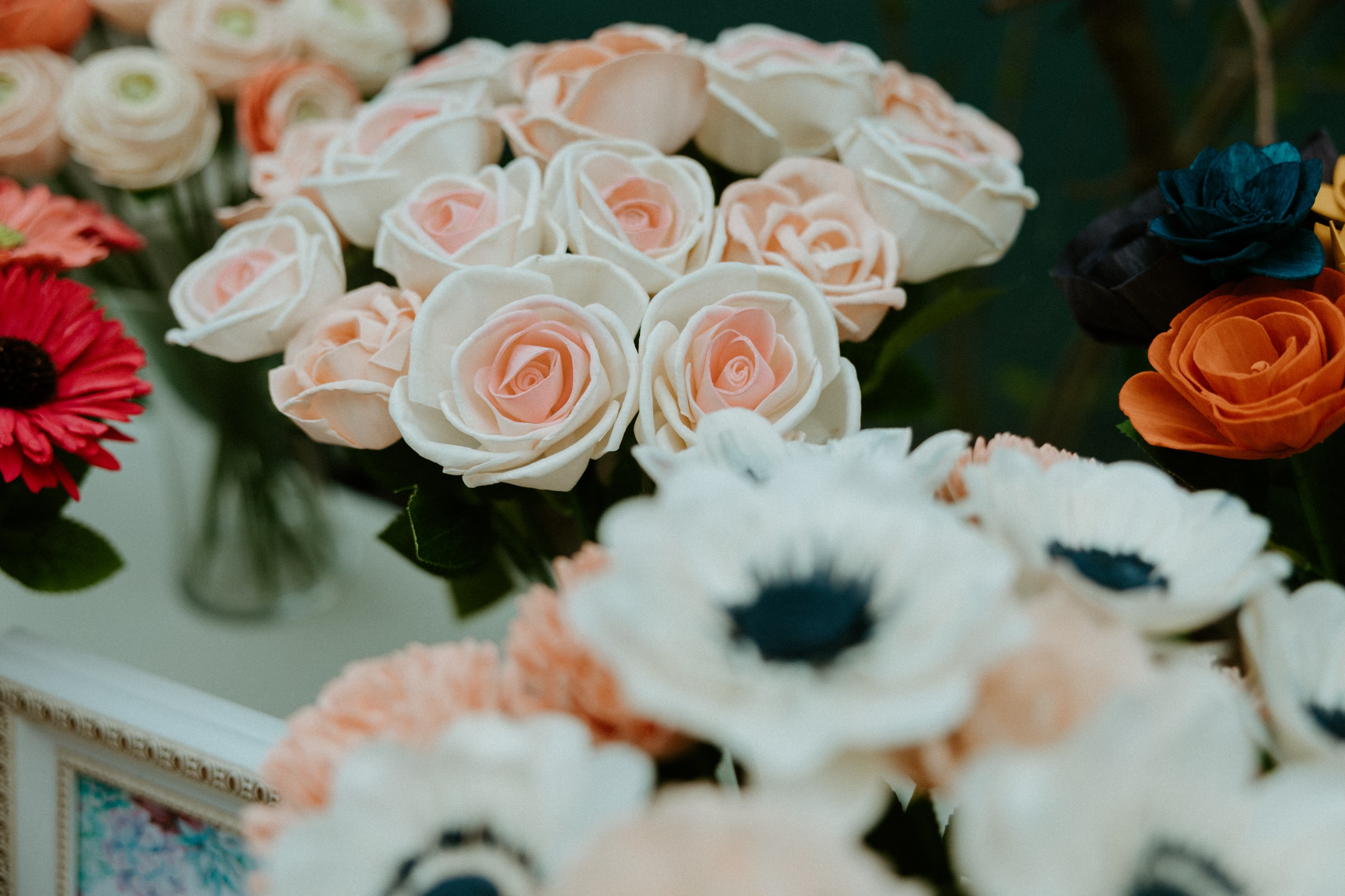 an up close image of two vases of wood flowers, white roses and anemones