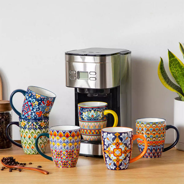 Boho-style coffee mugs filled with creamy latte, next to a coffee machine and scattered coffee beans