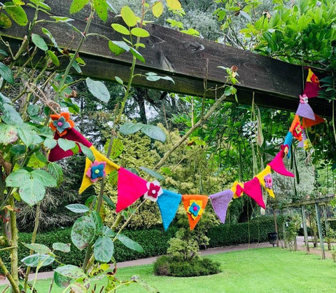 Colourful flag bunting hanging across a garden