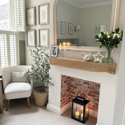 Neutral living space with an alcove with a black lantern in. Above the alcove is a solid wood mantel beam, and a mirror on the wall.