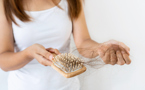 woman with hair loss on brush