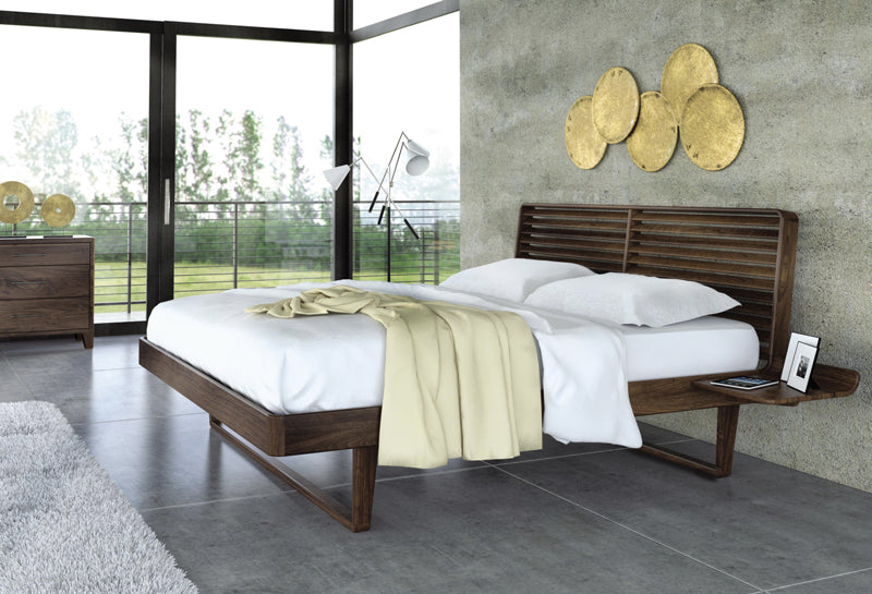 The Contour bed in natural walnut wood looks lovely beneath brass wall hangings.