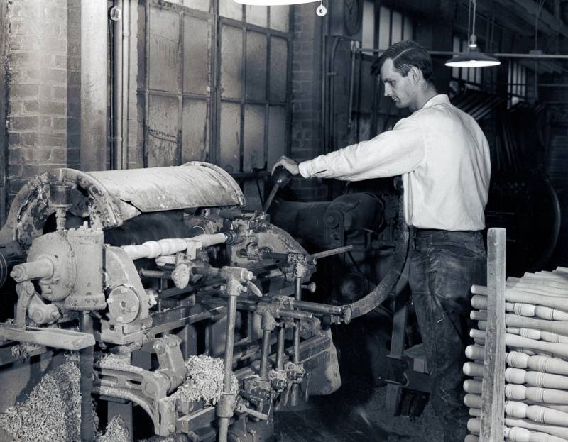 Cushman Furniture Factory worker turns wood table leg on lathe circa 1940.