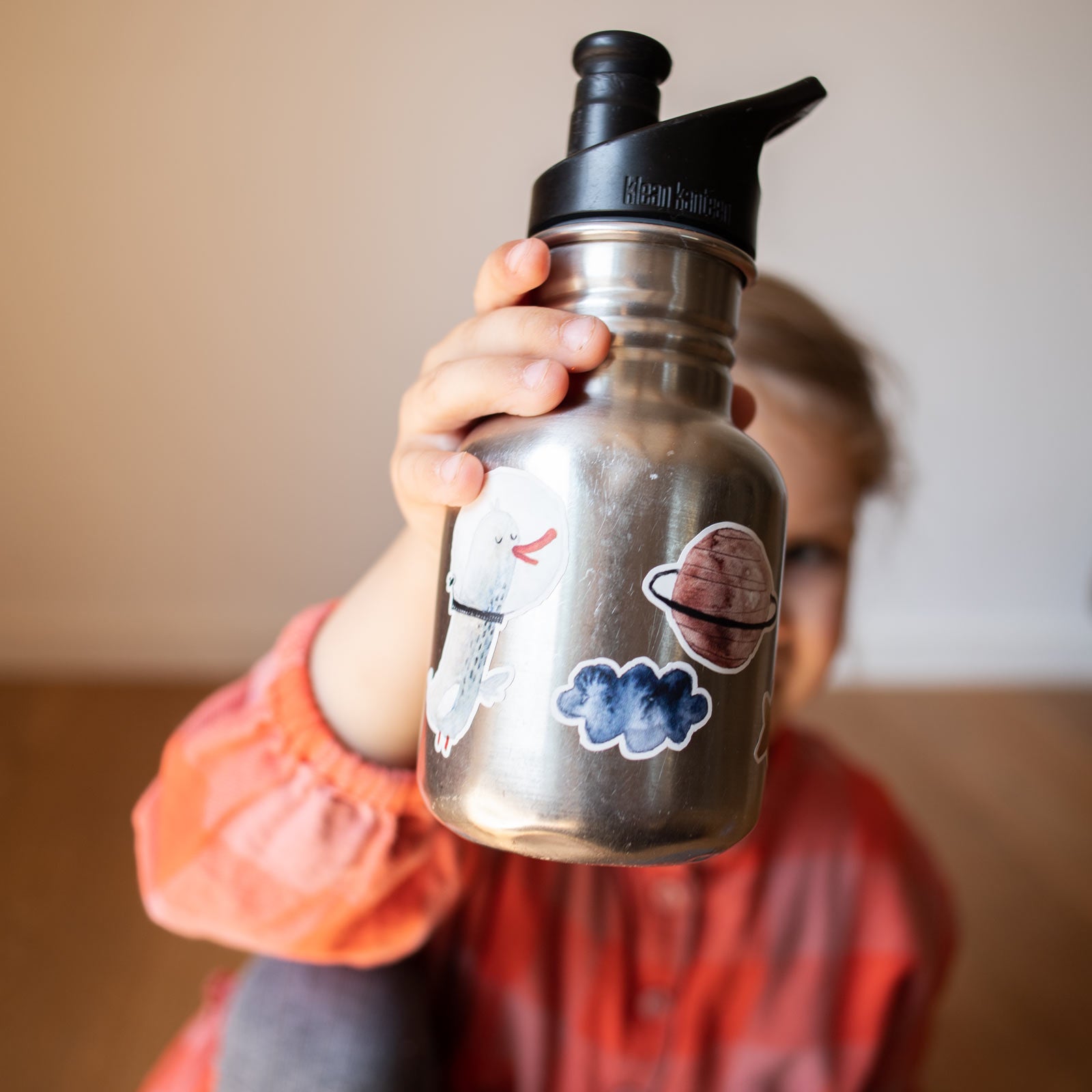 Kind hält Trinkflasche, die mit spülmaschinenfesten Stickern von Halfbird verziert ist