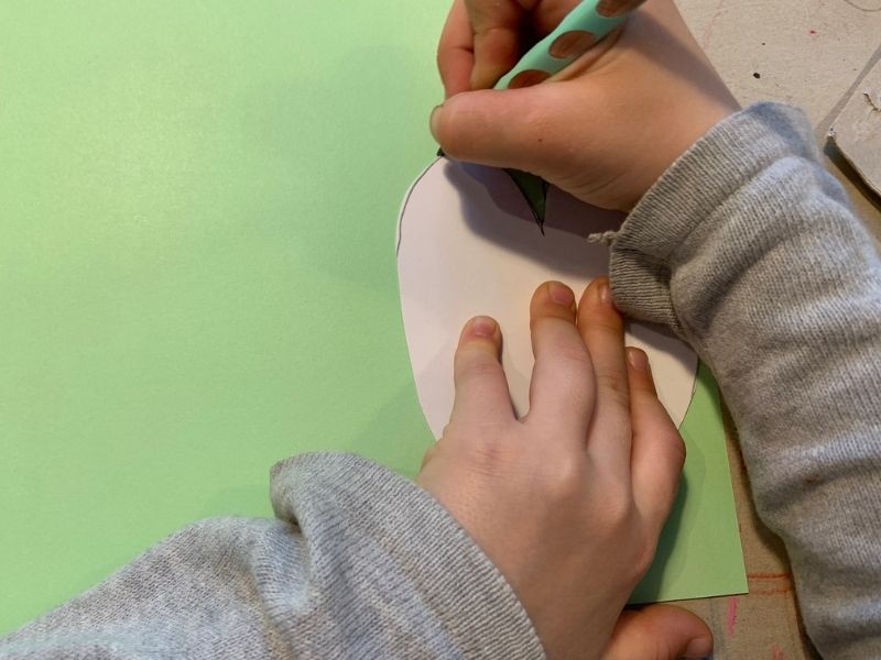 Kind malt um Schablone in Herzform